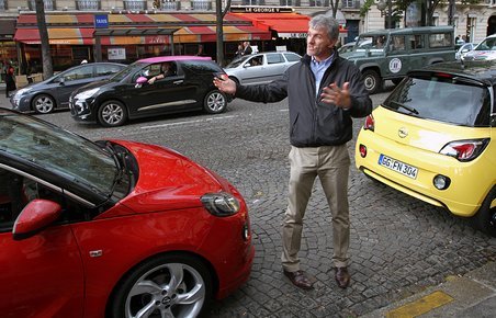 Opels chefdesigner Mark Adams præsenterer mærkets nye baby, Adam, midt i den parisiske trafik.