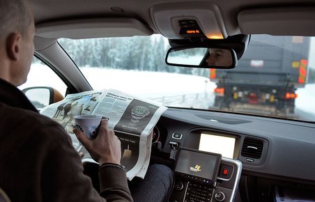 Uden hænder: Føreren i Volvo-testbilen kan læse avis, mens en lastbil "trækker" personbilen efter sig.